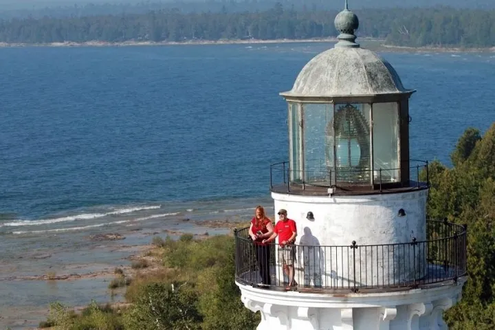 a small clock tower in front of a body of water
